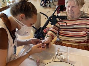 Bewohnerin erhält eine Maniküre von PflegemitarbeiterIn.