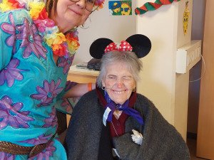 Mitarbeiterin stehend neben Bewohnerin im Rollstuhl sitzend, beide verkleidet für den Fasching.