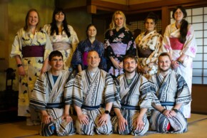 Zehn junge Teilnehmer:innen des Österreichisch-Japanischen Jugendaustauschs tragen Yukatas und posieren gemeinsam in einem traditionell eingerichteten japanischen Raum.