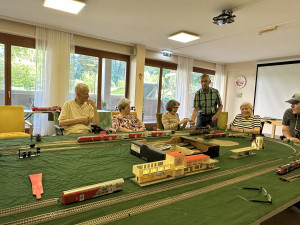 BewohnerInnen der SeniorInnenwohnanlage in Salzburg sitzend vor der Modelleisenbahn.