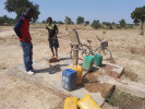Burkina Faso: Brunnen mit Kanistern und zwei Burschen, die Wasser holen.