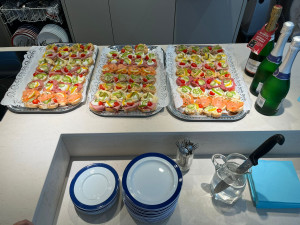 Belegte Brötchen auf Tableau daneben Sektflaschen auf Tisch.