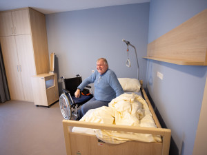 Senior sitzend auf dem Bett in einem Zimmer im neuen Pflegewohnhaus Neumargareten.