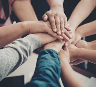 Symbolbild für Zusammenhalt: Hände die aufeinander liegen.