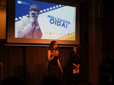 Eine Teilnehmerin von Afit NÖ, die an der Produktion der Kurzfilme beteiligt war, stehend einen Film vor Publikum präsentierend.