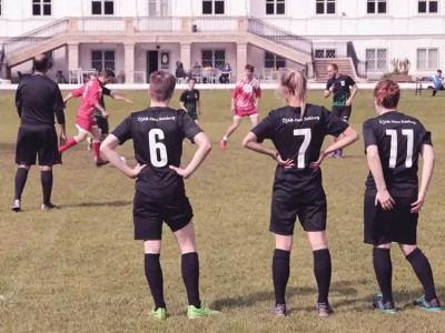 studentische TeilnehmerInnen des ÖJAB-Fussballturniers beobachten ein Fussballspiel am Spielrand. Im Hintergrund das Schloss Miller-Aichholz.