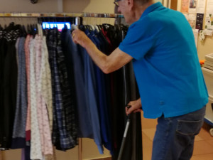 Bewohner durchstöbert eine Kleiderstange auf der Suche nach einem passenden Kleidungsstück.