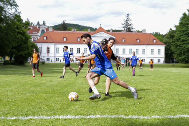 SpielerInnen im Zweikampf im Vordergrund. Im Hintergrund das Schloss Miller-Aichholz.