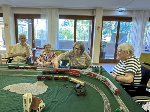BewohnerInnen der SeniorInnenwohnanlage in Salzburg sitzend vor der Modelleisenbahn.