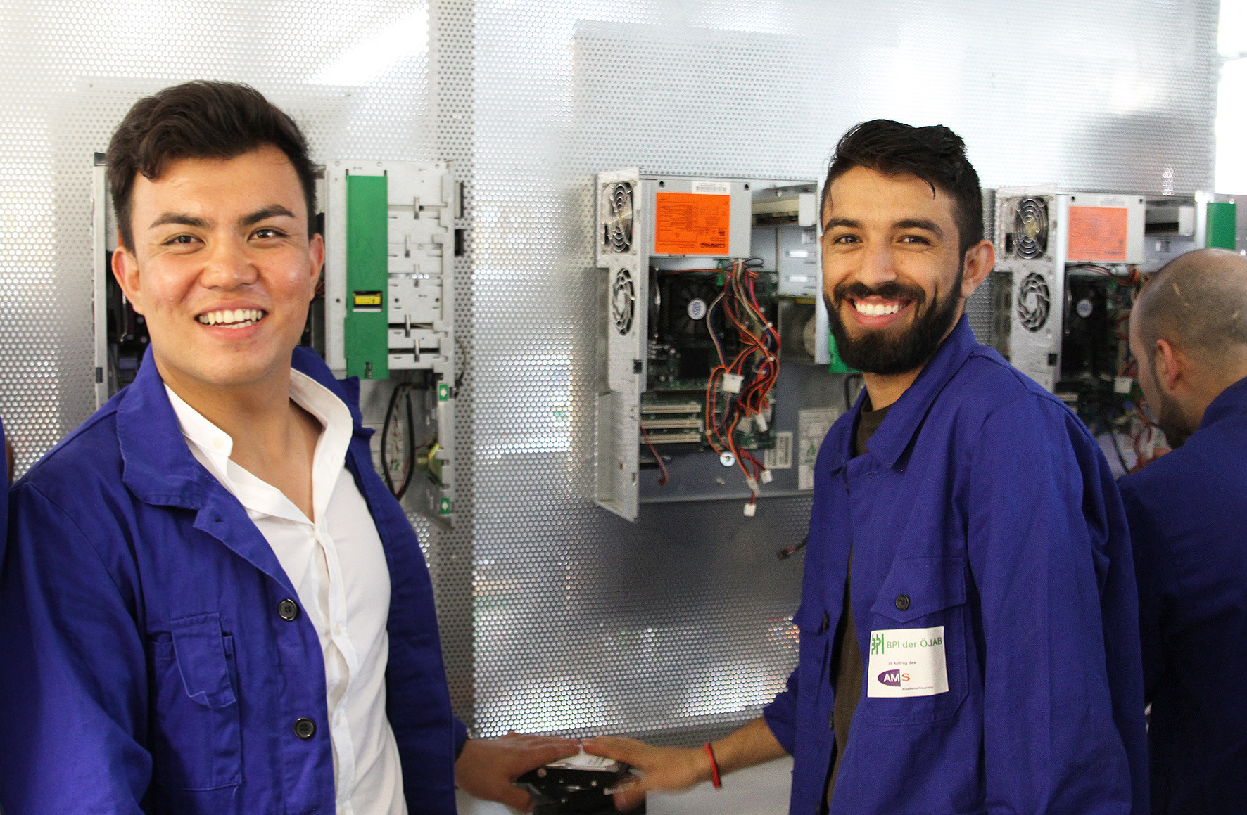Zwei Teilnehmer einer Berufsausbildung vor elektrotechnischen Anlagen