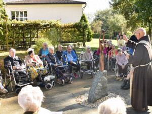 BewohnerInnen, sitzend, und Stadtpfarrer P. Raphael, stehend vor der Statue, bei der Segensfeier am 4. Oktober im Garten des Hauses.