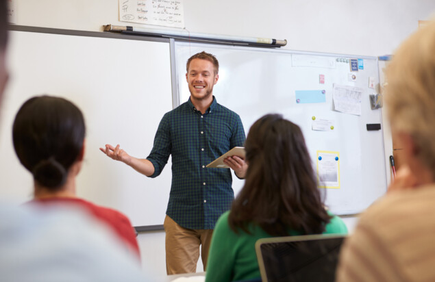 Ein Lehrer steht vor einer Klasse und unterrichtet.
