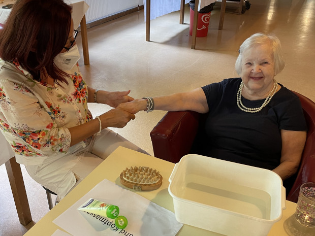 Bewohnerin erhält eine Handmassage von PflegemitarbeiterIn.