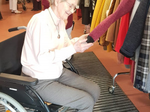 Bewohnerin sitzend vor dem mobilen Möbelverkauf.