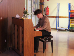 Musiker sitzend und spielend vor einem Klavier im Generationensaal des ÖJAB-Hauses Neumragareten.