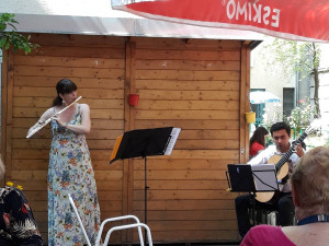 Nahaufnahme der Musikerin Marcela Lechtova an der Flöte und Romero Tizoc an der Gitarre im Garten des Wohn- und Pflegewohnheims.