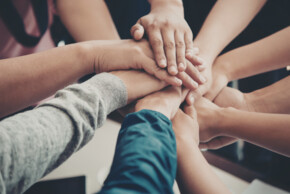 Symbolbild für Zusammenhalt: Hände die aufeinander liegen.