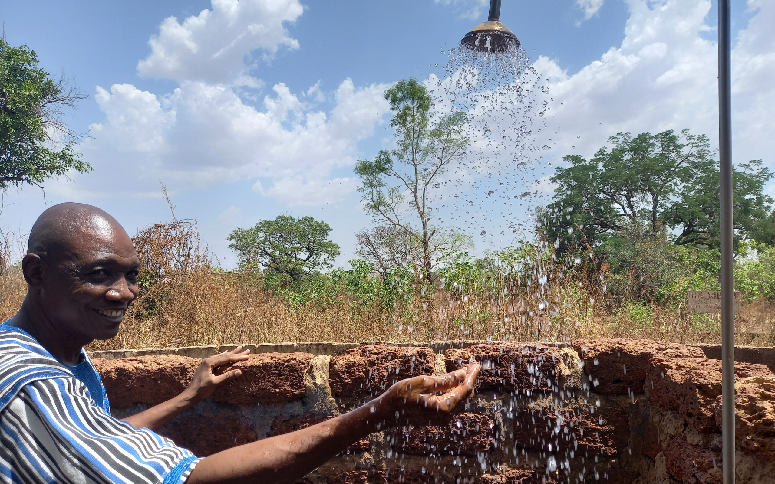 Burkinischer Mann stehend neben Dusche im Freien.
