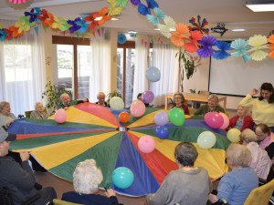 Bewohner:innen fröhlich im Kreis sitzend im Festsaal bei einer Aktivierungseinheit.