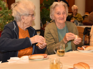 Zwei BewohnerInnen sitzend und Würstel essend.