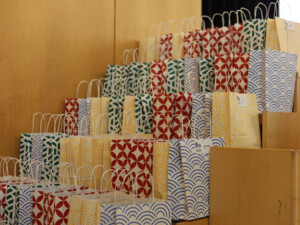 Viele bunt gemusterte Geschenktaschen sind ordentlich gestapelt und bereit zur Ausgabe an die Teilnehmenden.