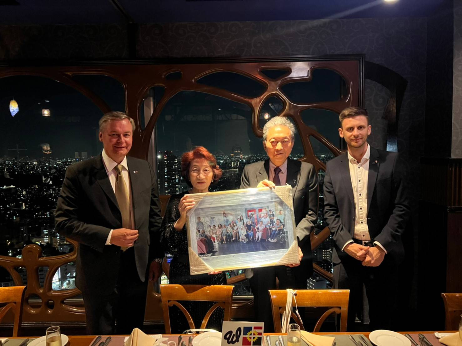 Gruppenfoto: Dieter Fröhlich (stellvertrtender Geschäftsführer der ÖJAB), Kuzuko Inoue (YUAI-Vorstandsmitlglied, langjährige Unterstützerin der Integrationsarbeit der ÖJAB), Yukio Hutoyama (YUAI-Präsident) und Georg Gaag (Brand Manager bei myNext Hotels, Apartments und Hostels) mit einem Bild in der Hand.