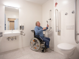 Senior im Rollstuhl in einem barrierefreien Badezimmer im ÖJAB-Pflegewohnhaus Neumargareten.
