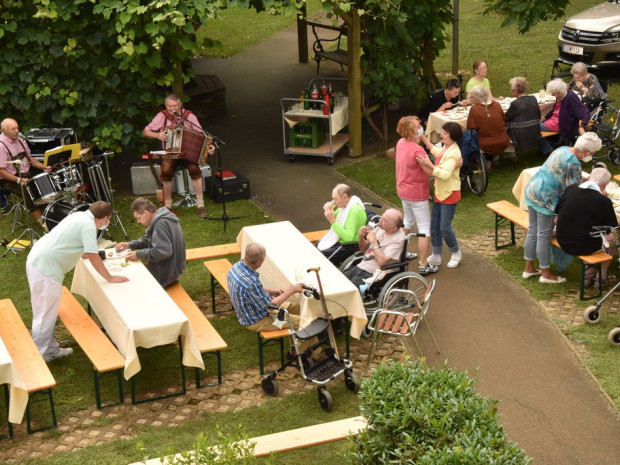 Aufnahme des Grillfestes von oben, BewohnerInnen und MusikerInnen sitzend und BewohnerInnen tanzend.