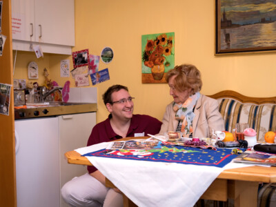 Pfleger mit Bewohnerin im Einzelzimmer des ÖJAB-Pflegewohnhauses Salzburg.