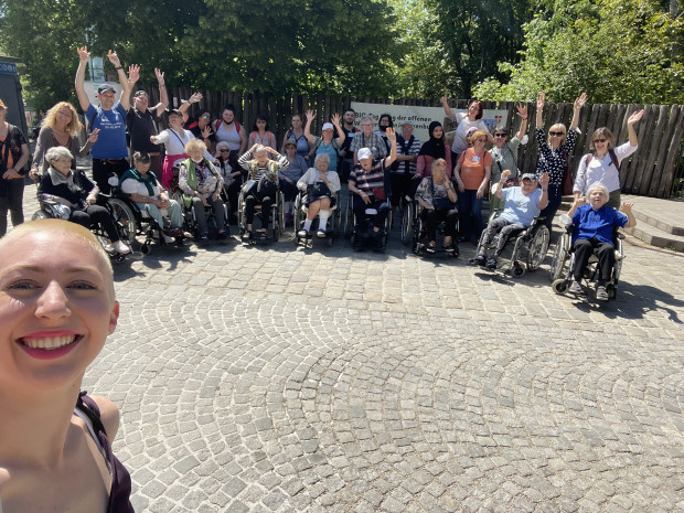 Gruppenfoto BewohnerInnen mit PflegemitarbeiterInnen vor  dem Eingang des Lainzer Tiergartens.