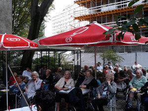 Musiker mit dem Rücken zur Kamera vor Publikum im Garten des Wohn- und Pflegewohnheims.