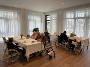 BewohnerInnen und PflegemitarbeiterInnen in einem Gemeinschaftsraum des ÖJAB-Pflegewohnhauses Neumargareten.
