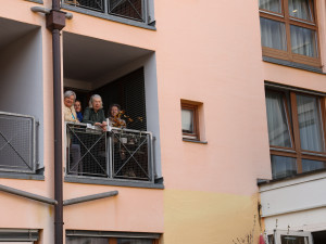 Bewohner:innen des Hauses am Balkon stehend.