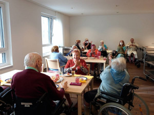 BewohnerInnen an Tischen im neuen ÖJAB-Pflegewohnhaus gemeinsam sitzend bei einem Sektempfang.