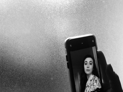 Hand hält Handy. Auf dem Handy ist ein Portrait einer Dame erkennbar.