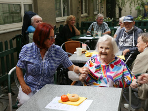 BewohnerInnen und Mitarbeiterin sitzend im Garten des ÖJAB-Hauses Neumargareten.
