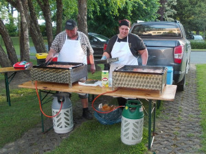 Die Grillstation mit zwei Gasgrillern. Im Hintergrund stehend MitarbeiterInnen.