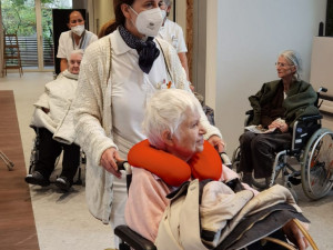 Bewohnerin in Rollstuhl wird von Pflegemitarbeiterin durch die neuen Räumlichkeiten des ÖJAB-Pflegewohnhauses geführt.