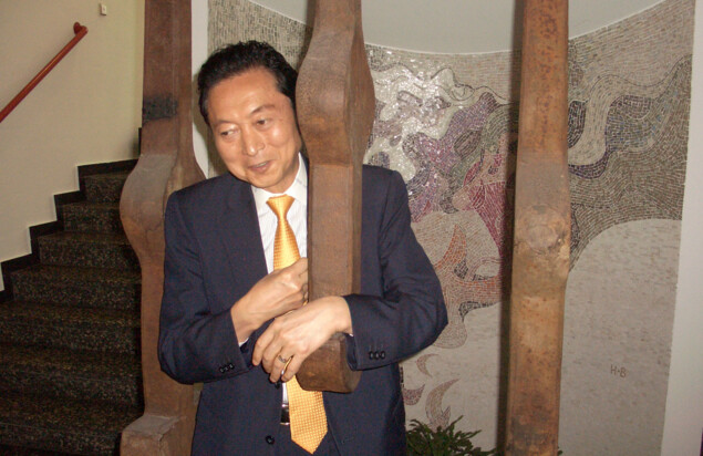 Photo of Yukio Hatoyama and Petra Heidler standing in a traditional Japanese room and shaking hands with each other.