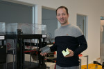 Mario Jakic, operativer Leiter des Berufspädagogischen Instituts (BPI) der ÖJAB, mit einem 3-D-Drucker und zwei Kunststoff-Formen, die am BPI der ÖJAB im 3-D-Druckverfahren hergestellt wurden.