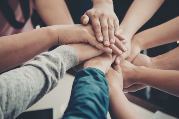 Symbolbild für Zusammenhalt: Hände die aufeinander liegen.