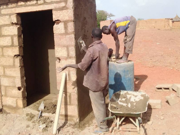 Two local Burkinabe craftsmen building a latrine in the Burkinabe community of Samba.