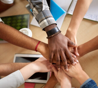 Symbolbild. Mehre Hände überneinander. Symbol für Gemeinschaft.