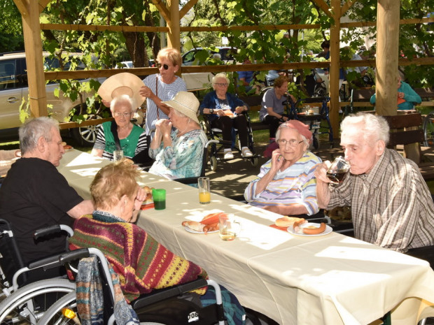 BewohnerInnen sitzend beim Frühlingsfest in der Gartenlaube des ÖJAB-Hauses St. Franziskus.