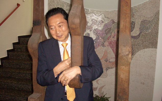 Photo of Yukio Hatoyama and Petra Heidler standing in a traditional Japanese room and shaking hands with each other.