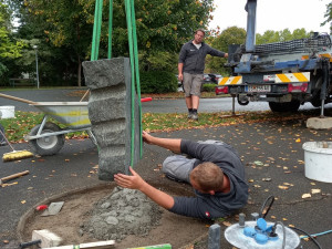 Mitarbeiter der Firma Stein-Schwarz, liegend, beim Errichten des Sockels für die neue St. Franziskusstatue.