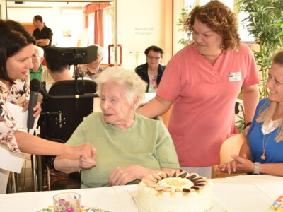 Elfriede Geosits (86) umgeben von Mitarbeiter:innen des Heimes.
