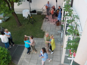 MitarbeiterInnen des Hauses beim "Danke Fest" tanzend im Garten. Rechts im Hintergrund MusikerInnen.