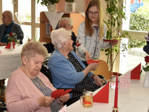 Schülerin übergibt Heimbewohnerin ein selbstgemachtes Herz.