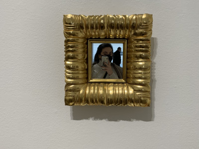 Quadratischer goldener Bilderrahmen mit Foto, auf Wand aufgehangen.